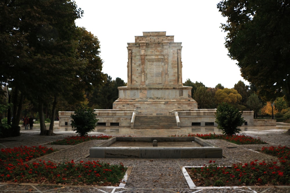 a monument in a park surrounded by trees and flowers