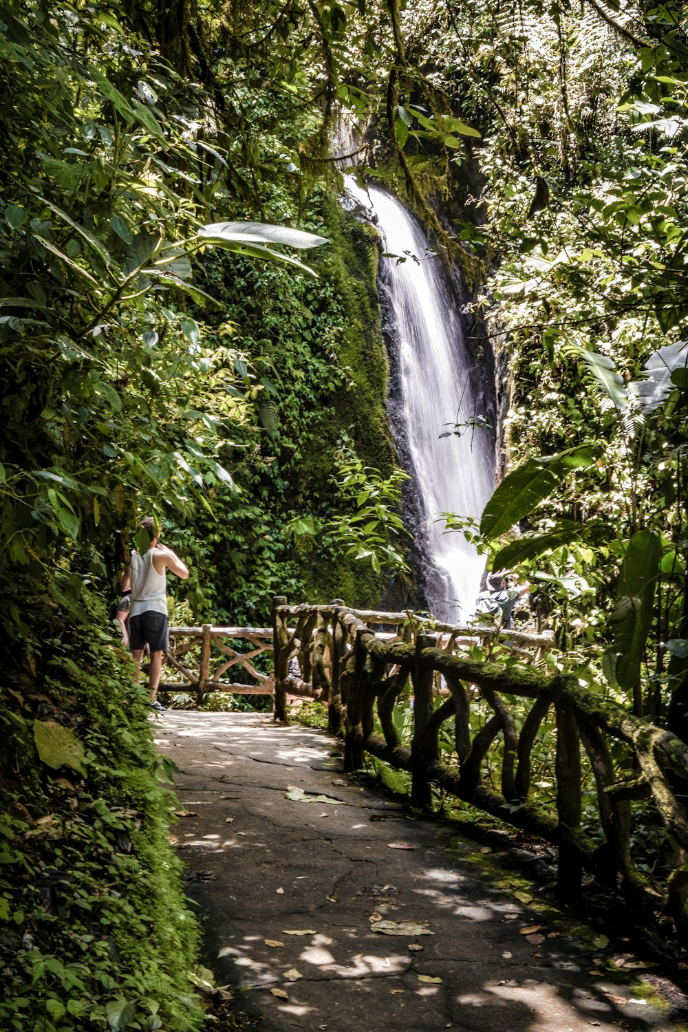 a man standing on a bridge next to a waterfall