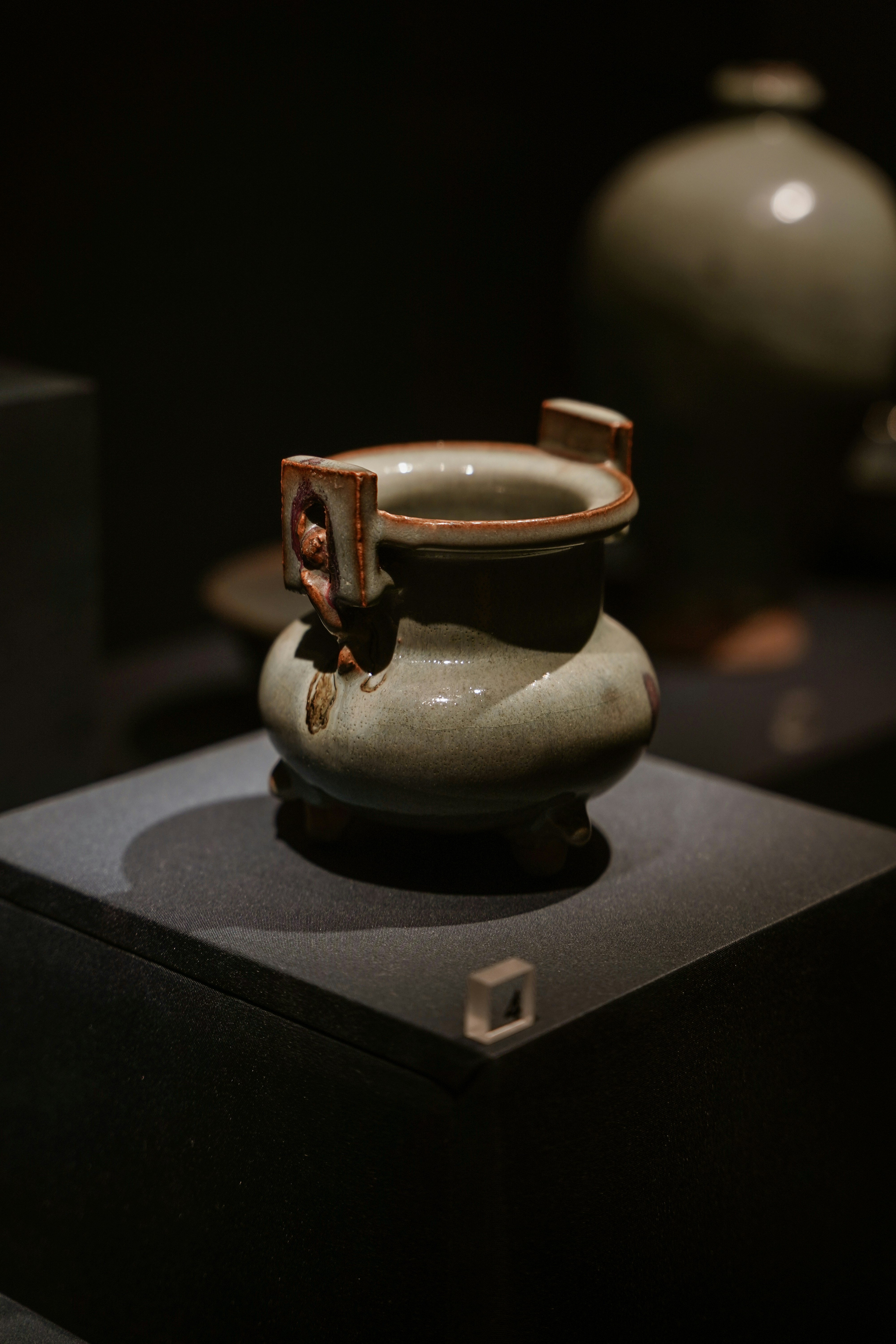 a white vase sitting on top of a black box