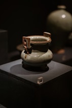 a white vase sitting on top of a black box