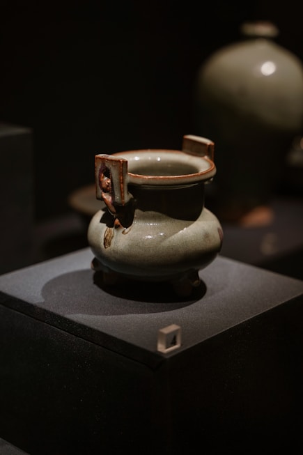 a white vase sitting on top of a black box