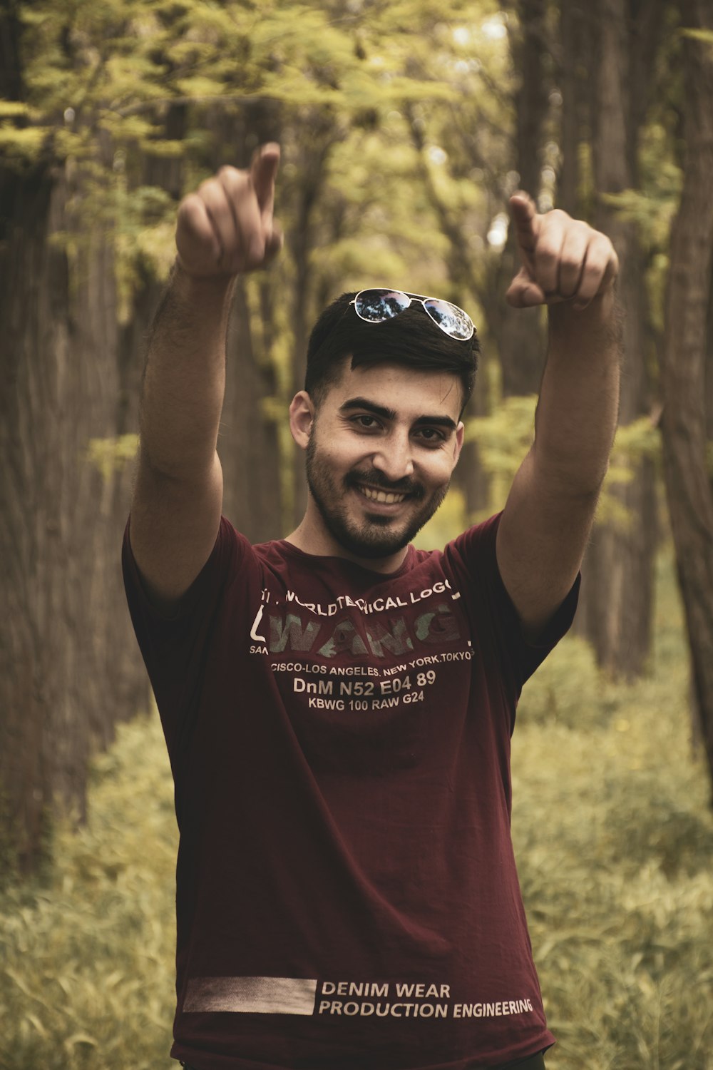 a man standing in a forest with his arms in the air