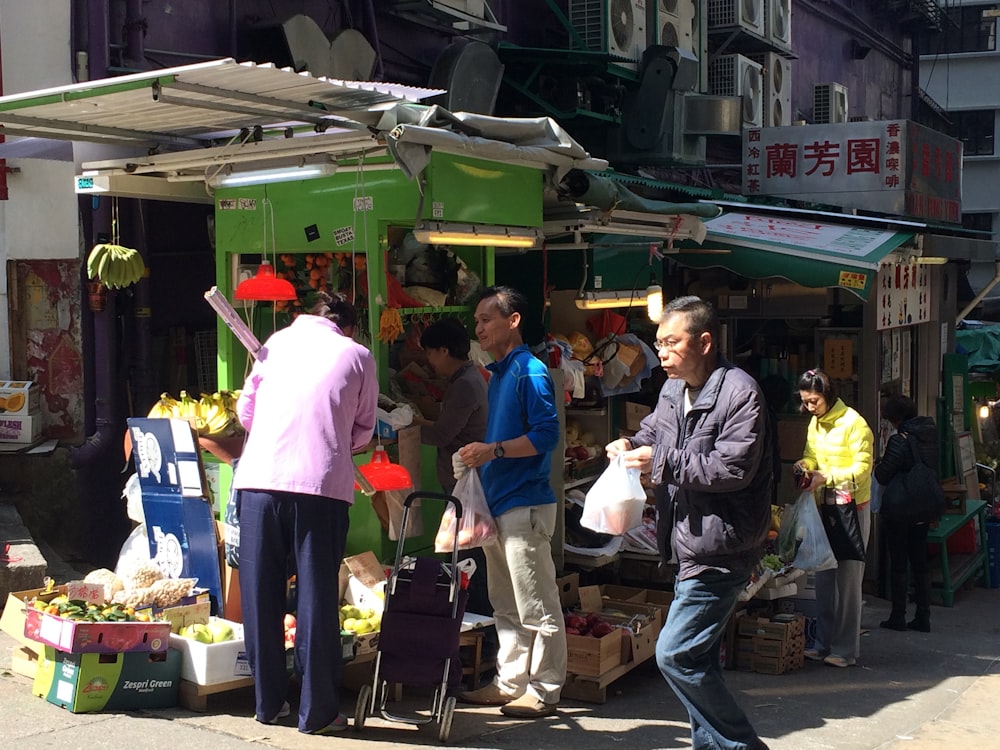 a group of people standing around a fruit stand
