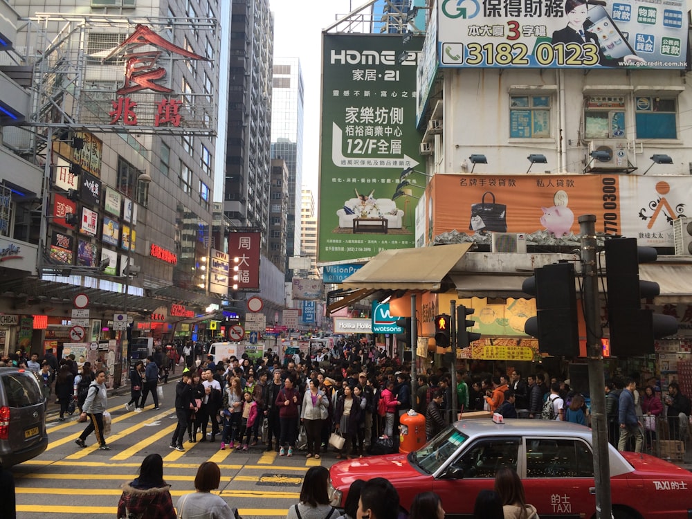 a crowd of people walking across a street next to tall buildings