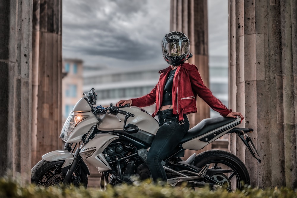 a woman in a red jacket is sitting on a motorcycle