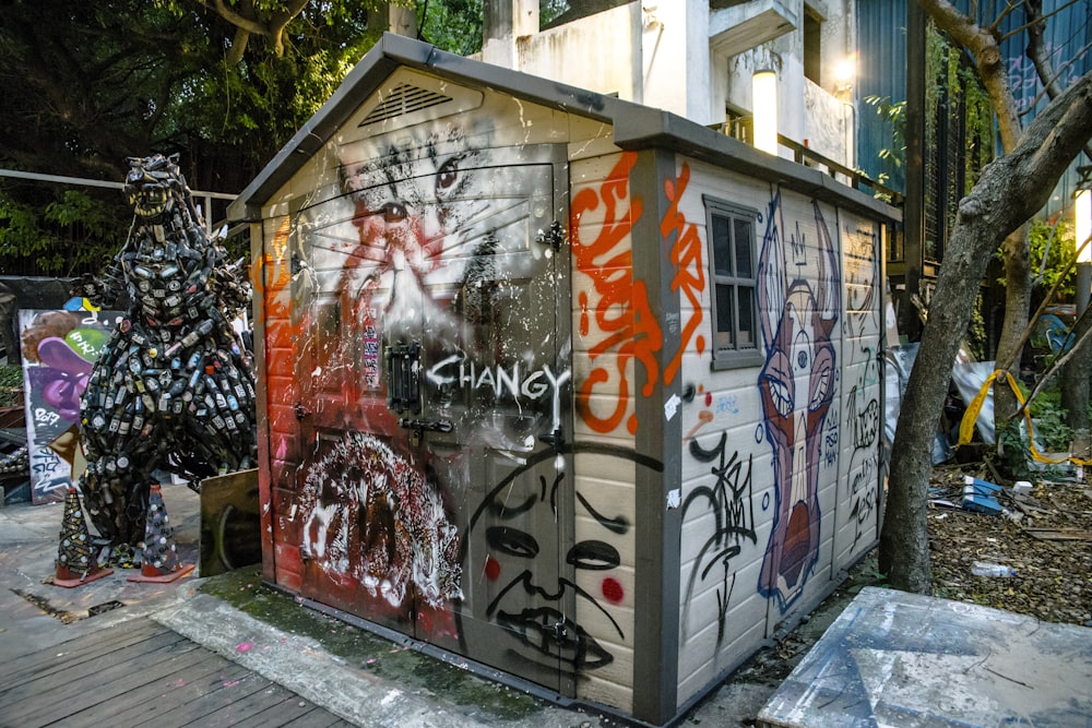 a shack covered in graffiti next to a tree