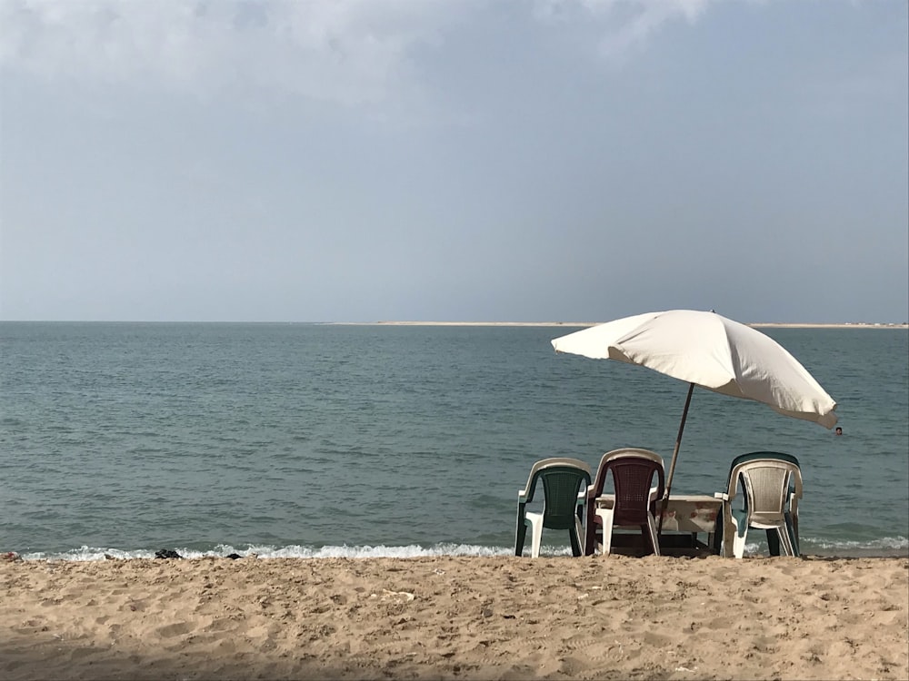 a couple of chairs sitting under an umbrella on a beach