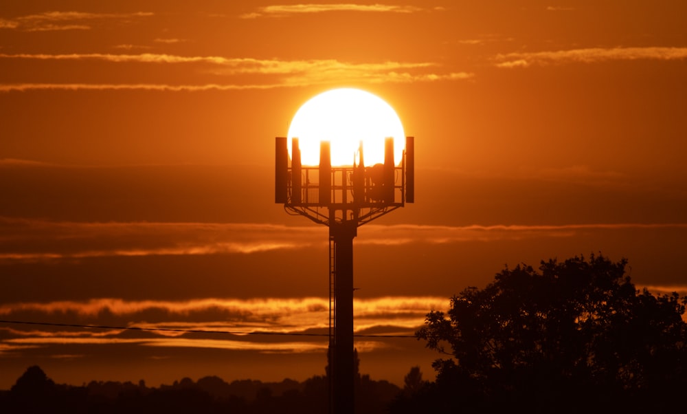 Il sole sta tramontando dietro una torre con un telefono cellulare su di esso