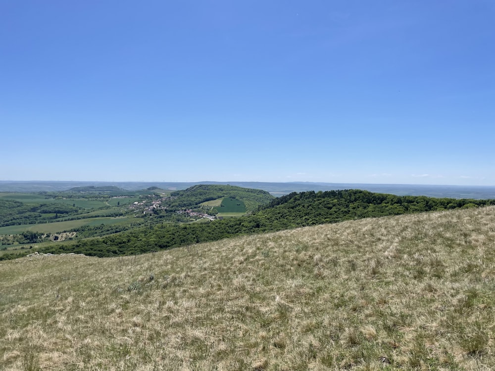 a grassy hill with a valley in the distance