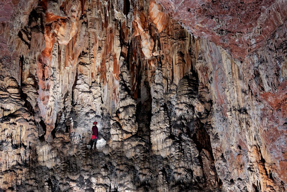 two people standing in a cave with a mountain in the background