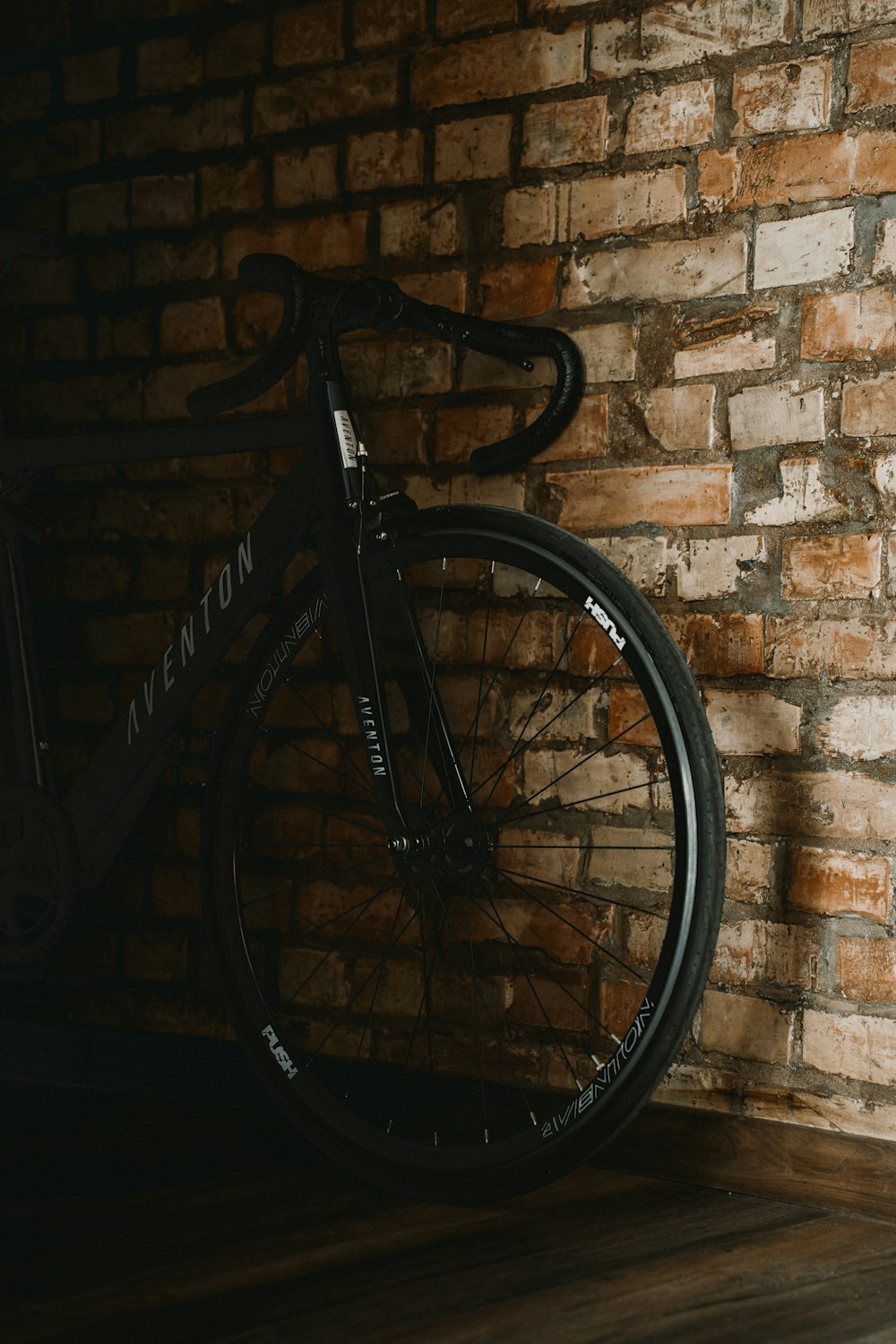 a black bike leaning against a brick wall