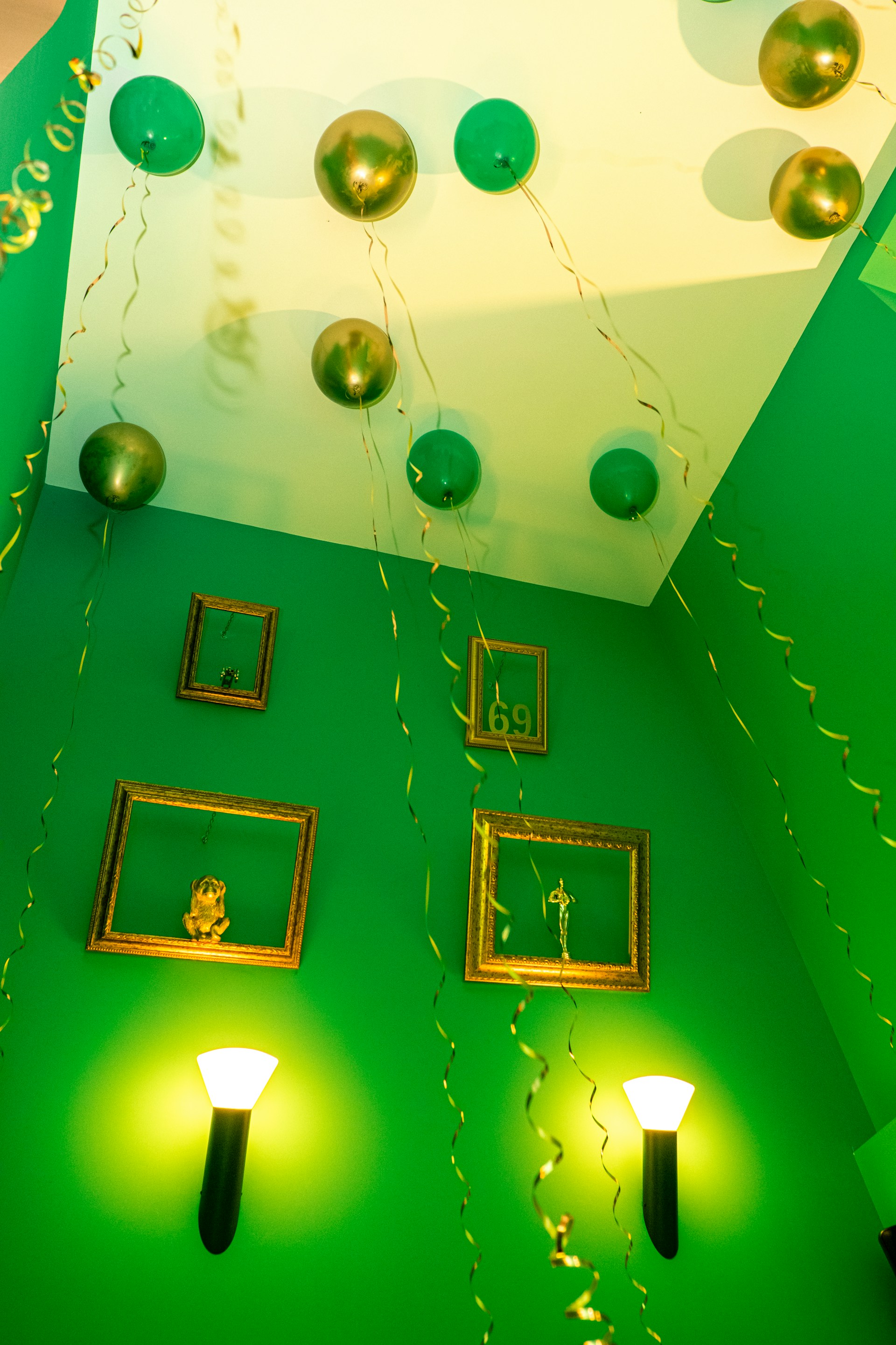 A vibrant party room decorated in bright green with ladybug-themed balloons and table settings.