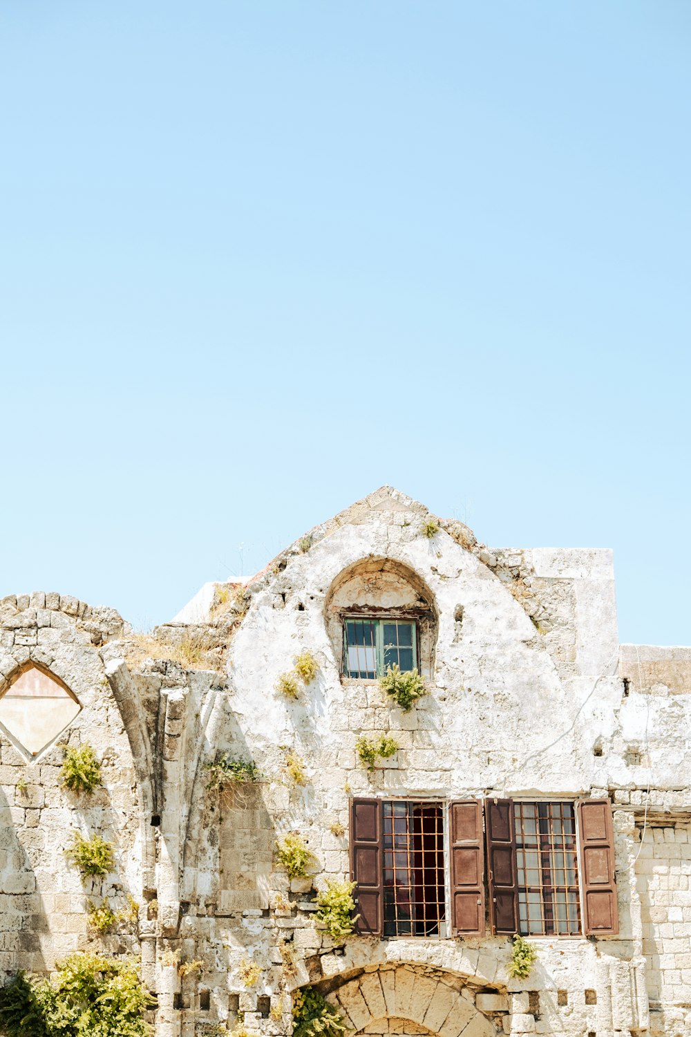 a stone building with two arched windows and shutters