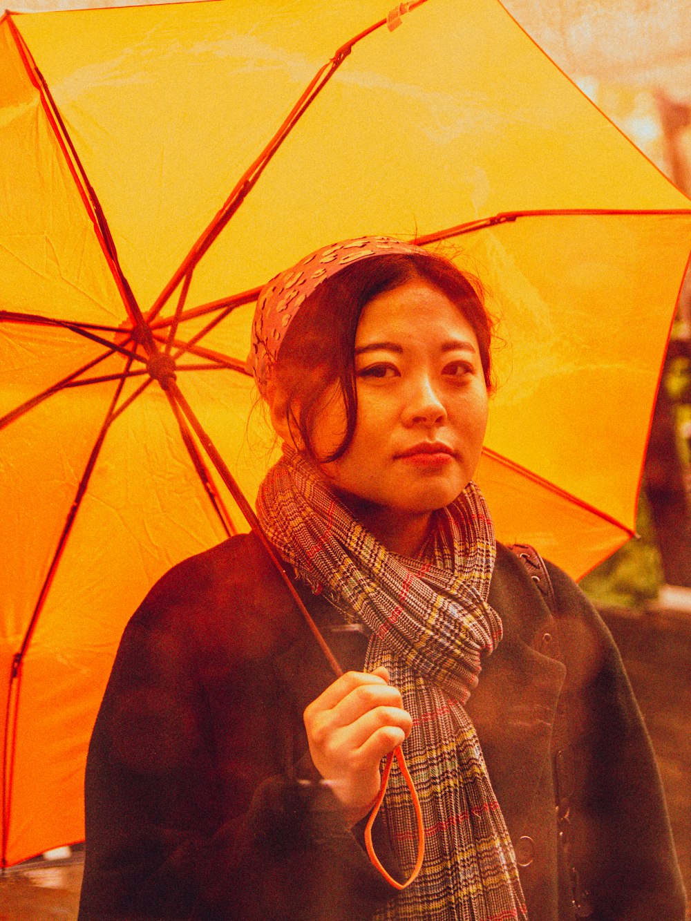 a woman holding an orange umbrella in the rain