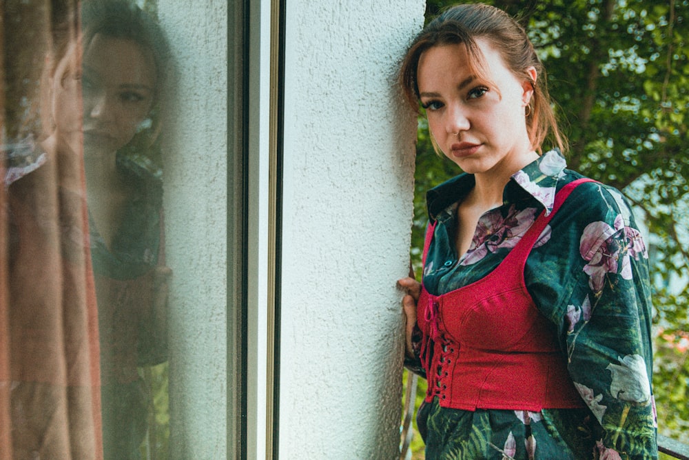 a woman leaning against a window with her hand on her hip