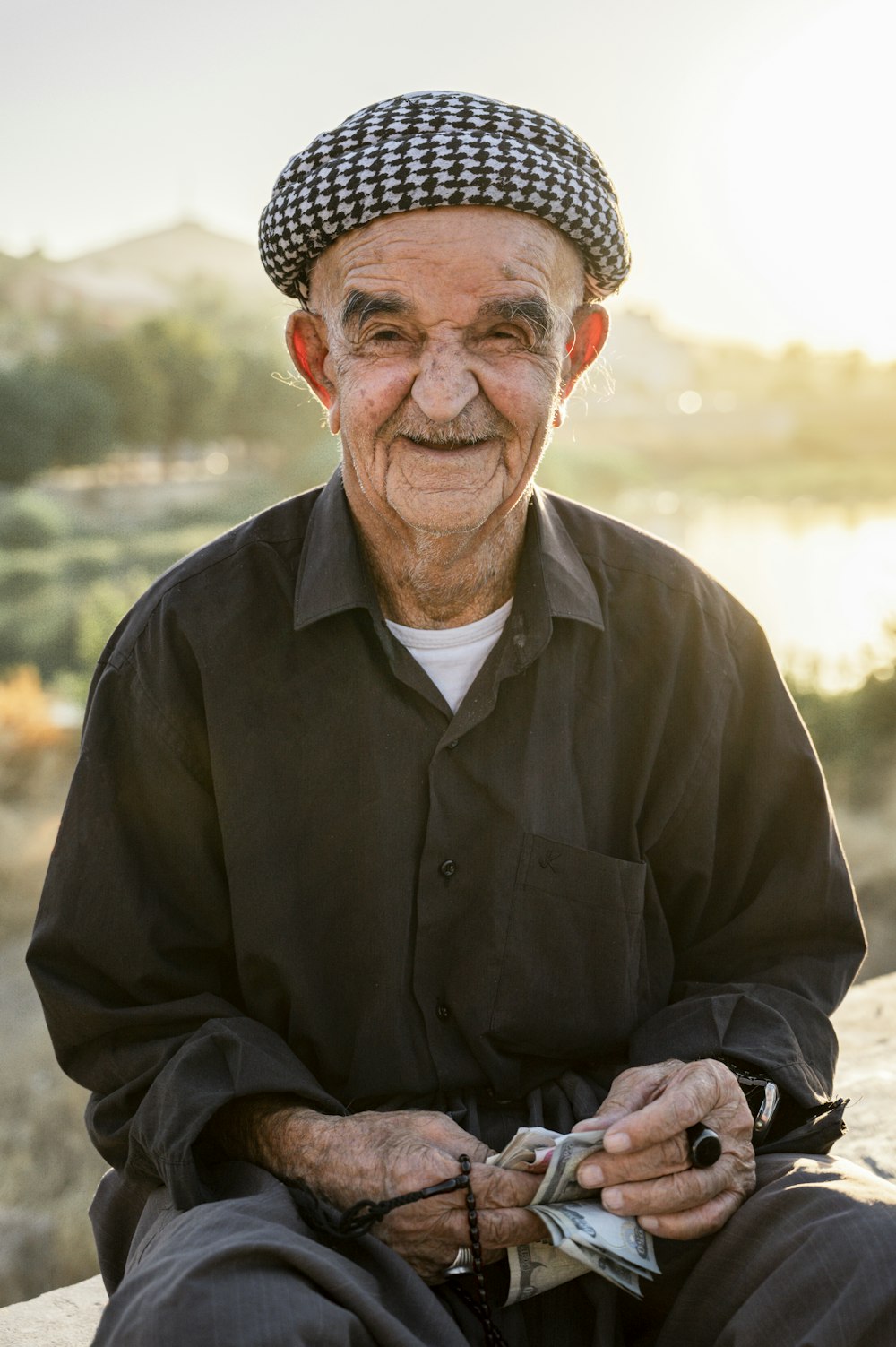 an old man sitting on a rock with a hat on