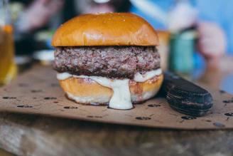 Juicy homemade hamburger with melted cheese and fresh toppings on a wooden table.