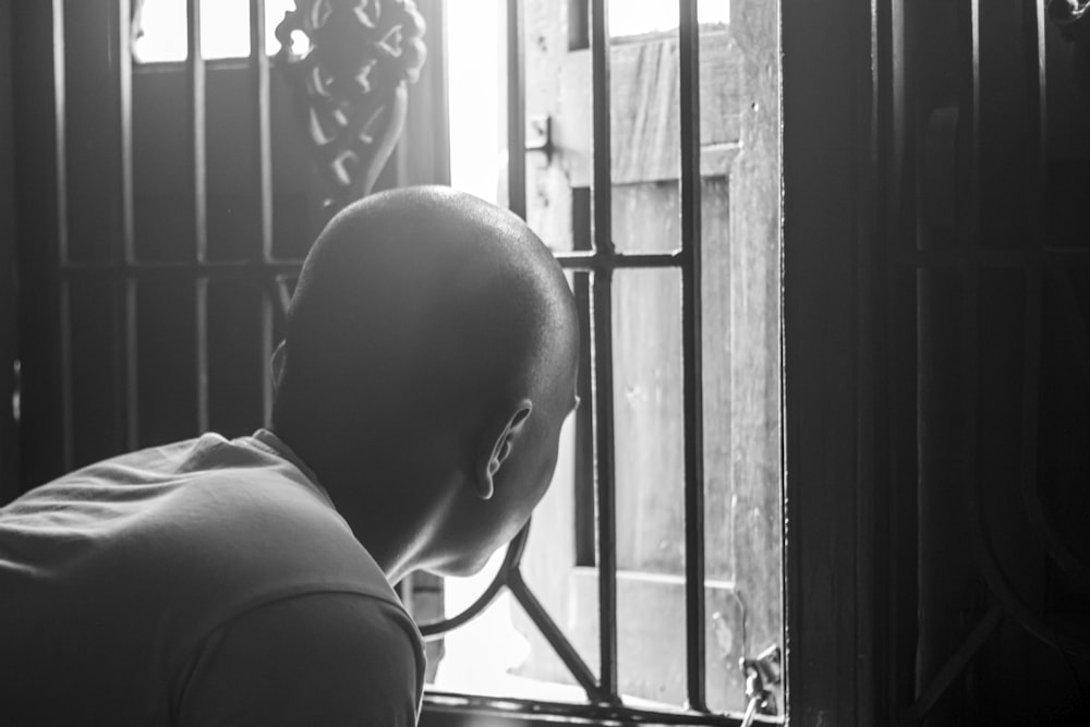 a bald man looking out of a window
