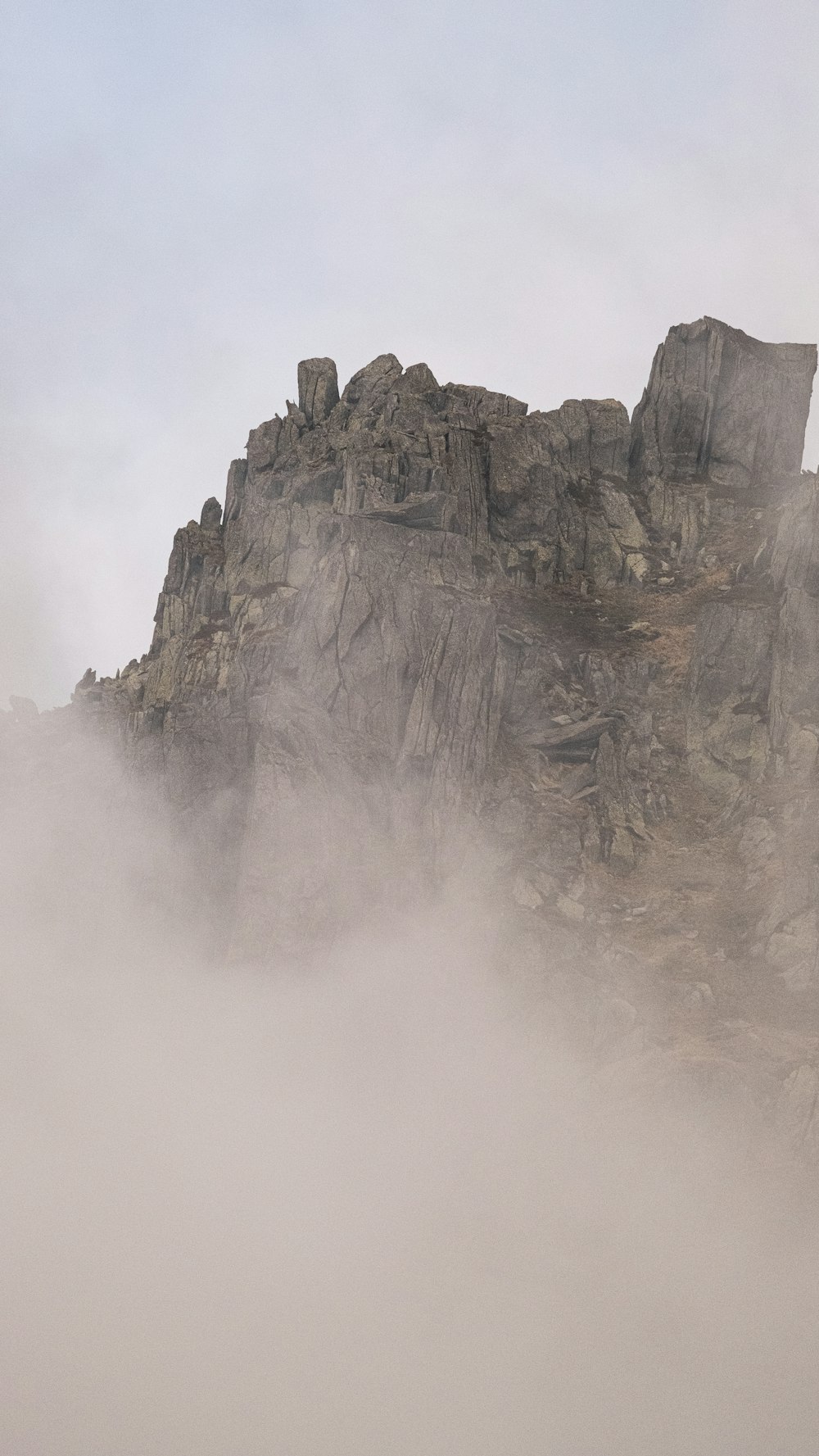 a large rock formation in the middle of a foggy mountain