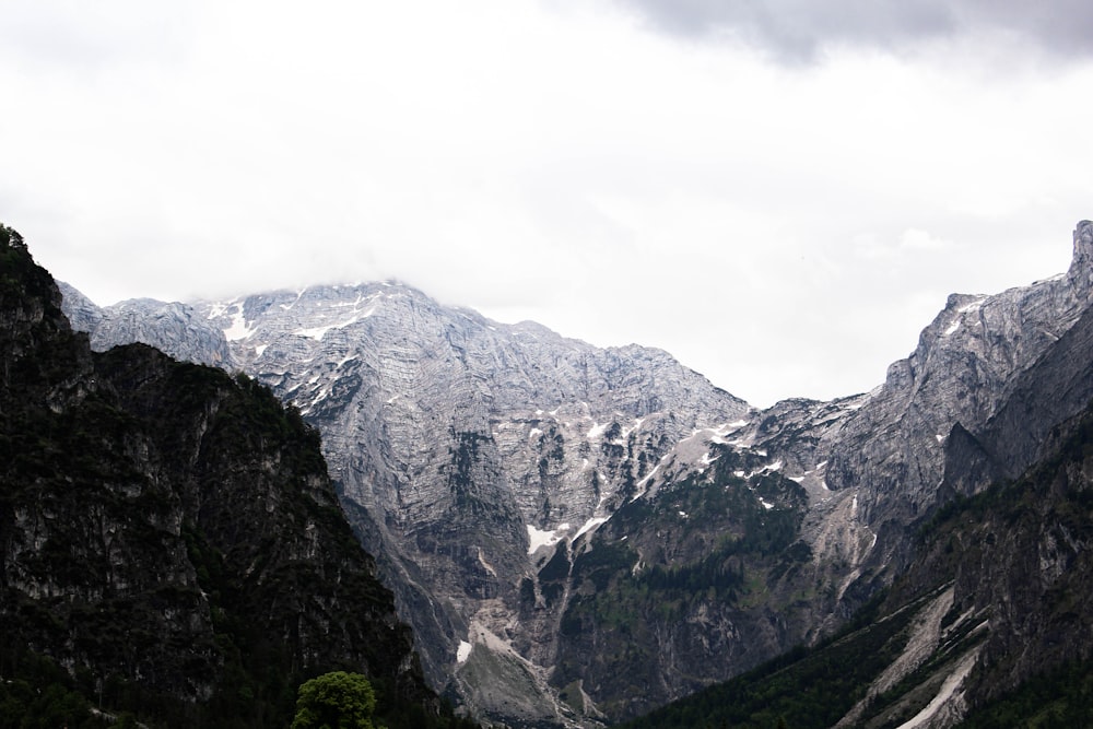 the mountains are covered in snow and green trees