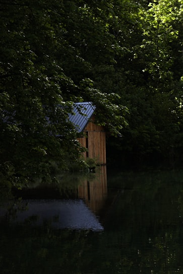 Modern corrugated steel retreat nestled among eucalyptus trees by the calm Blackwood River at sunset.