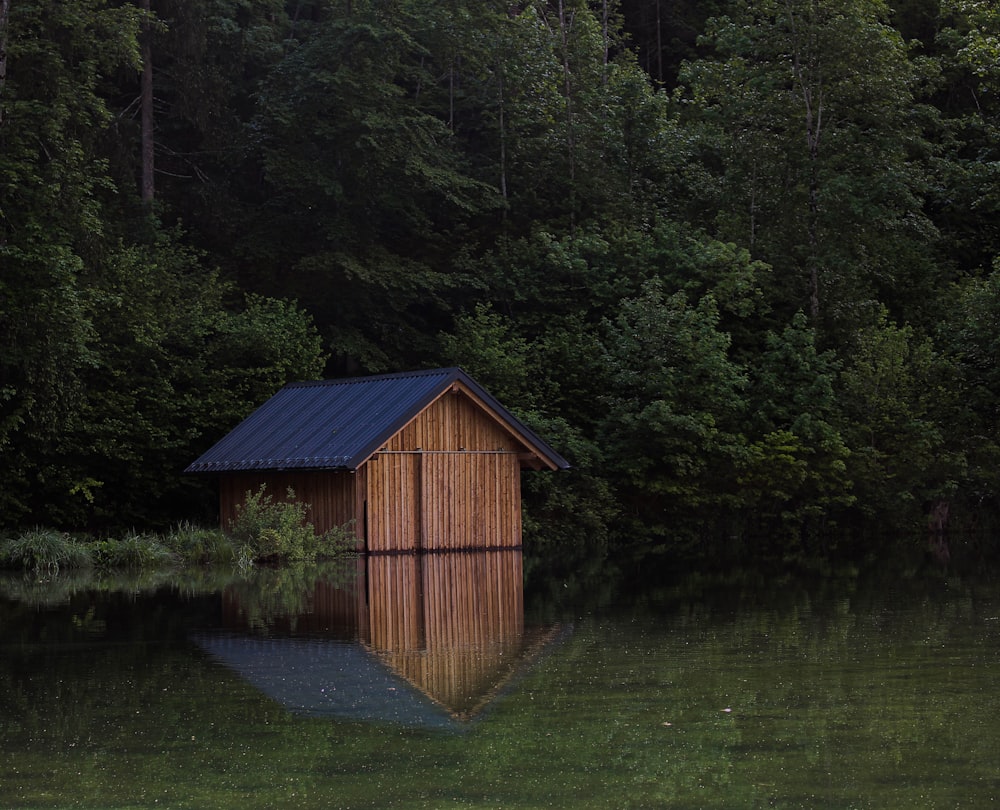 a small wooden shed sitting in the middle of a lake