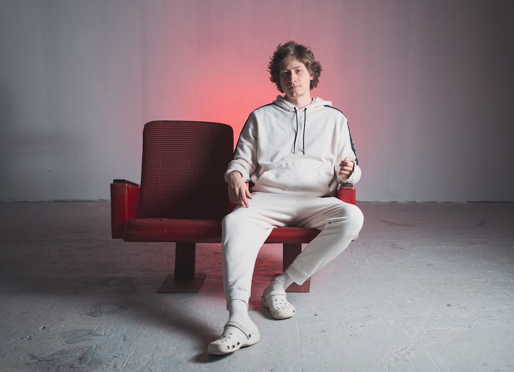 a woman sitting on a red bench in a white sweatshirt and sweatpants