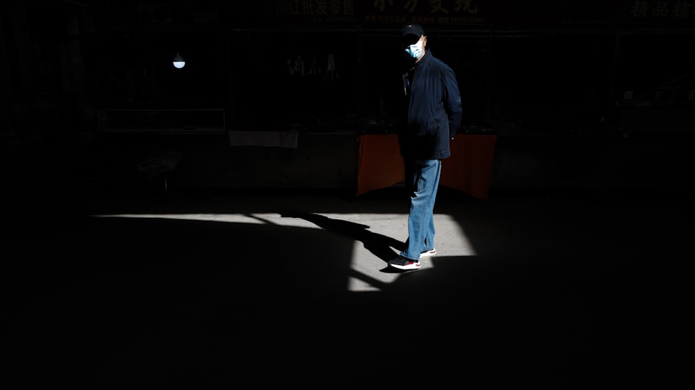 a man standing in the dark wearing a face mask