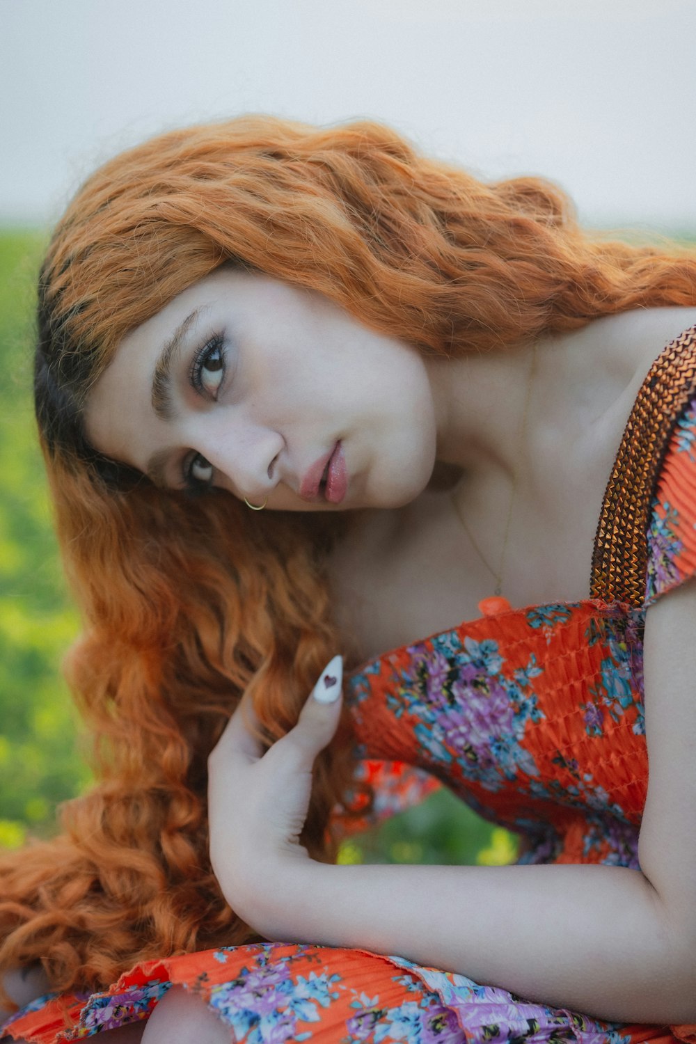 a woman with red hair sitting in a field