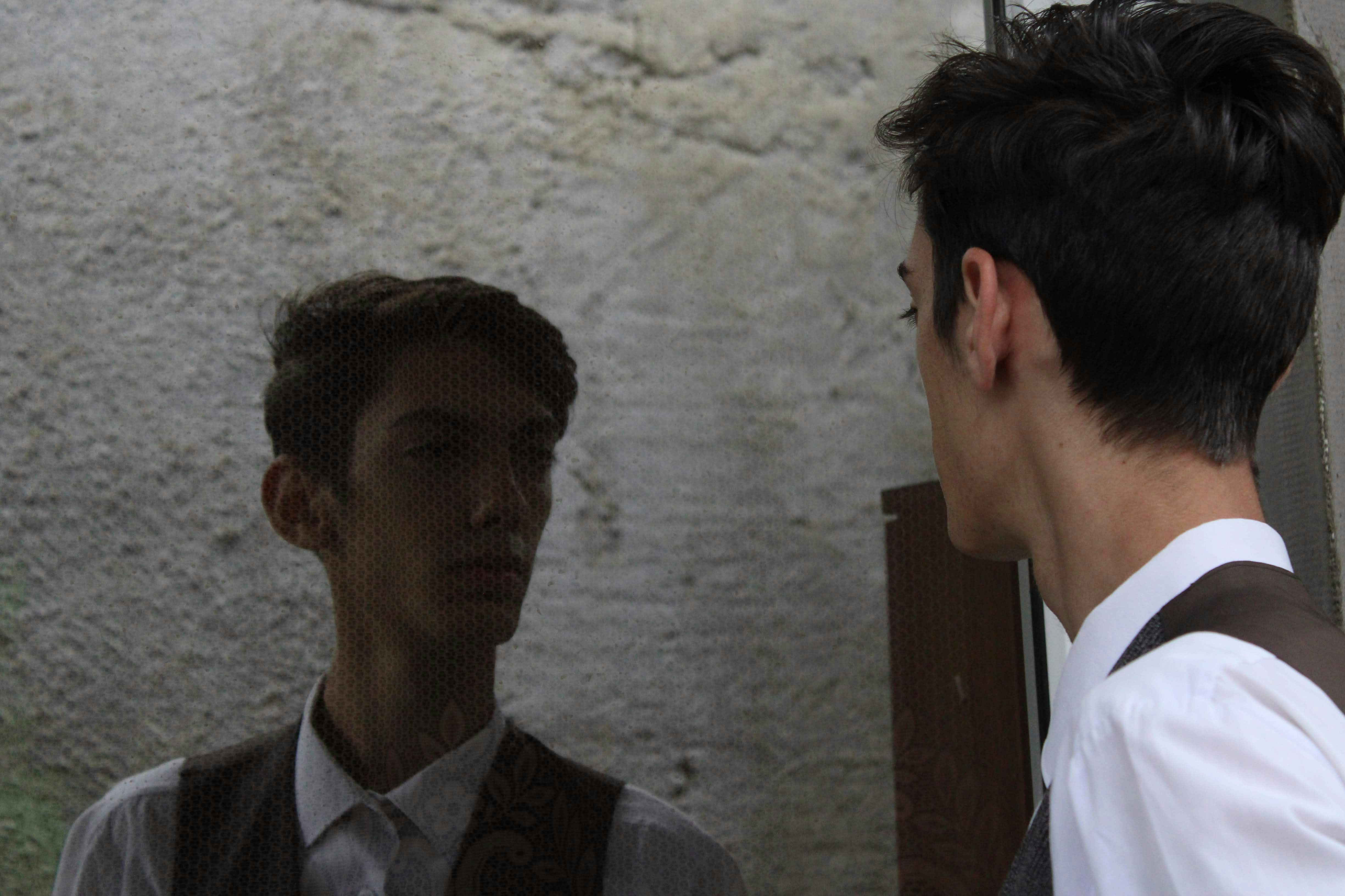 Un hombre parado frente a un espejo junto a otro hombre