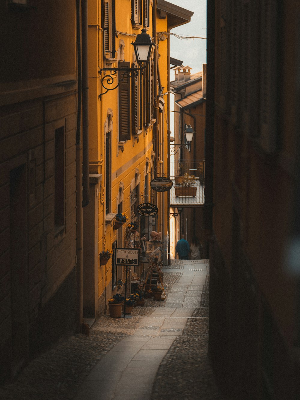 a narrow alley way with a yellow building in the background