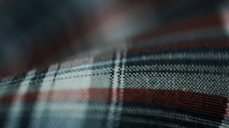 Close-up of a vintage Scottish tartan fabric draped over a wooden table.