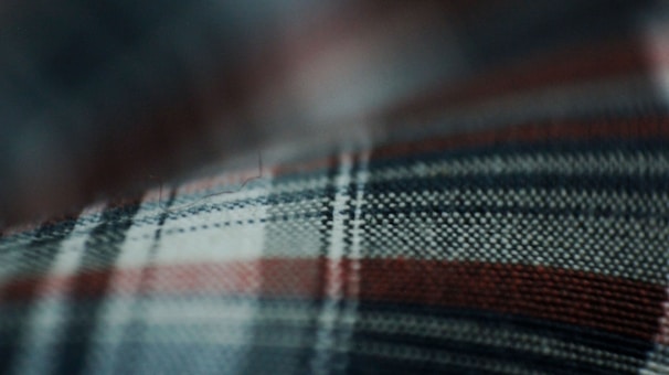 Close-up of a vintage Scottish tartan fabric draped over a wooden table.