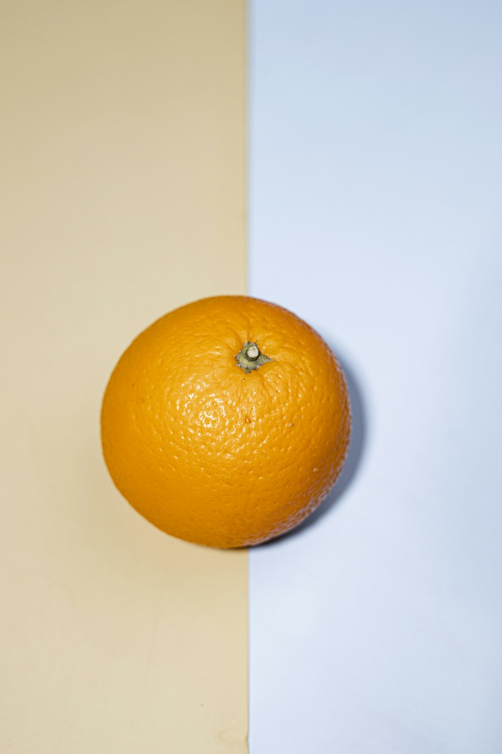 an orange sitting on top of a table next to a white wall