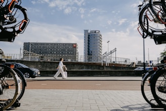 a woman walking down a street next to parked bikes