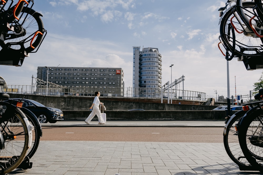 a woman walking down a street next to parked bikes