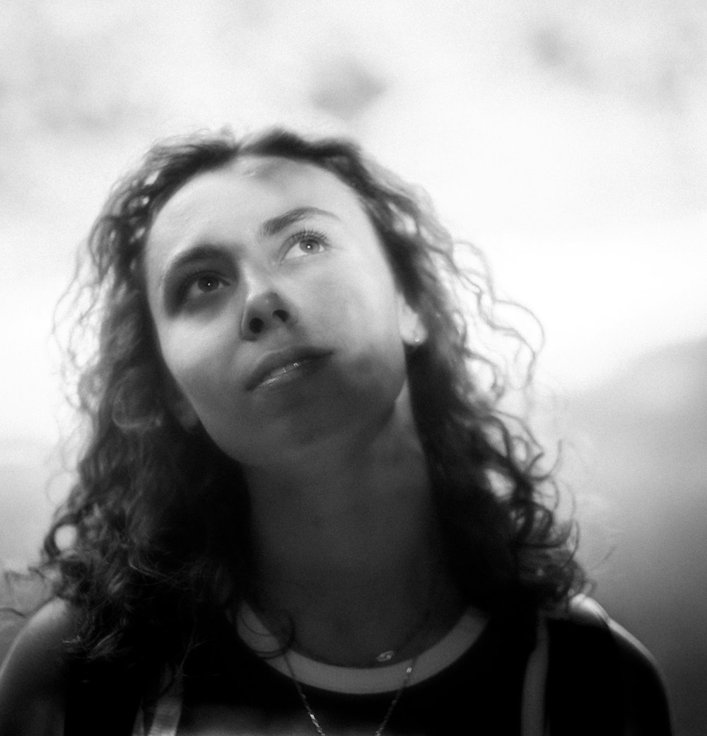 a black and white photo of a woman looking up