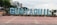 Large, colorful letters spelling 'GUAYAQUIL' are prominently displayed in a public area. The letters are set against a backdrop of tall buildings and a ferris wheel. There are plants and trees surrounding the display, adding greenery to the scene.