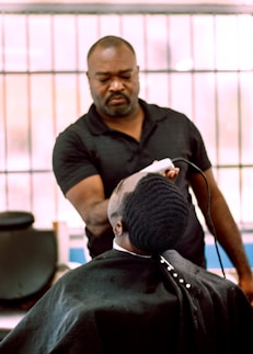 a man cutting another mans hair in a barber shop