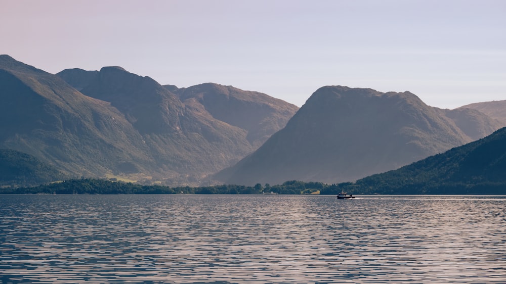 a boat on a large body of water with mountains in the background