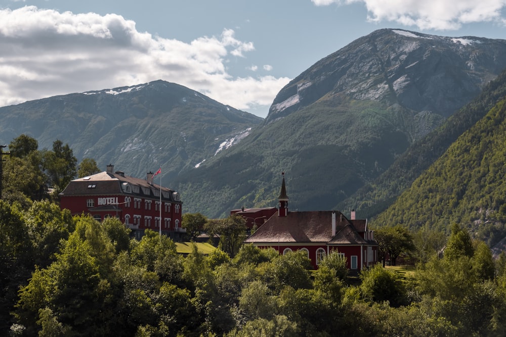 a large red building surrounded by trees and mountains