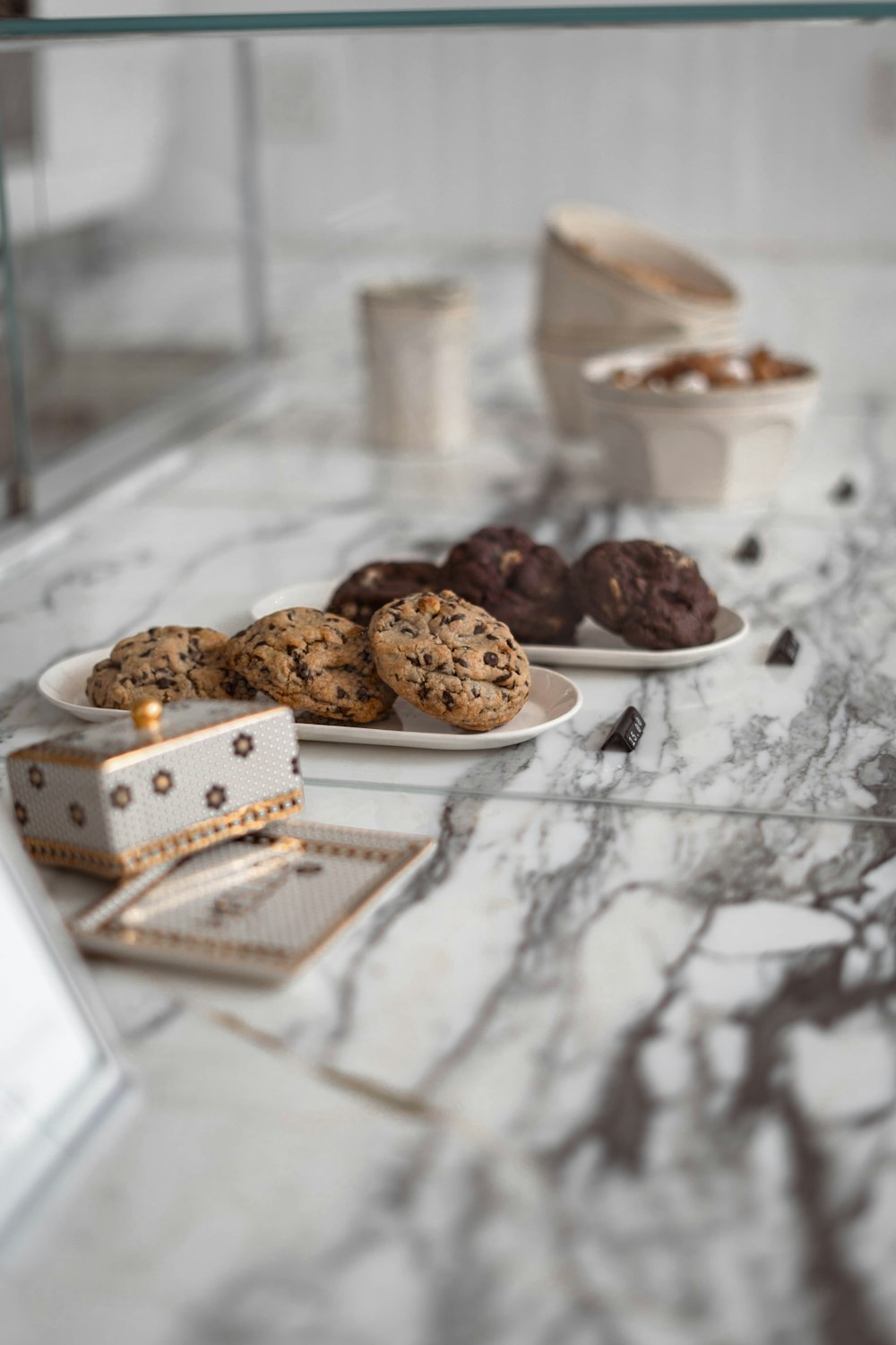 a marble table topped with plates of cookies and muffins