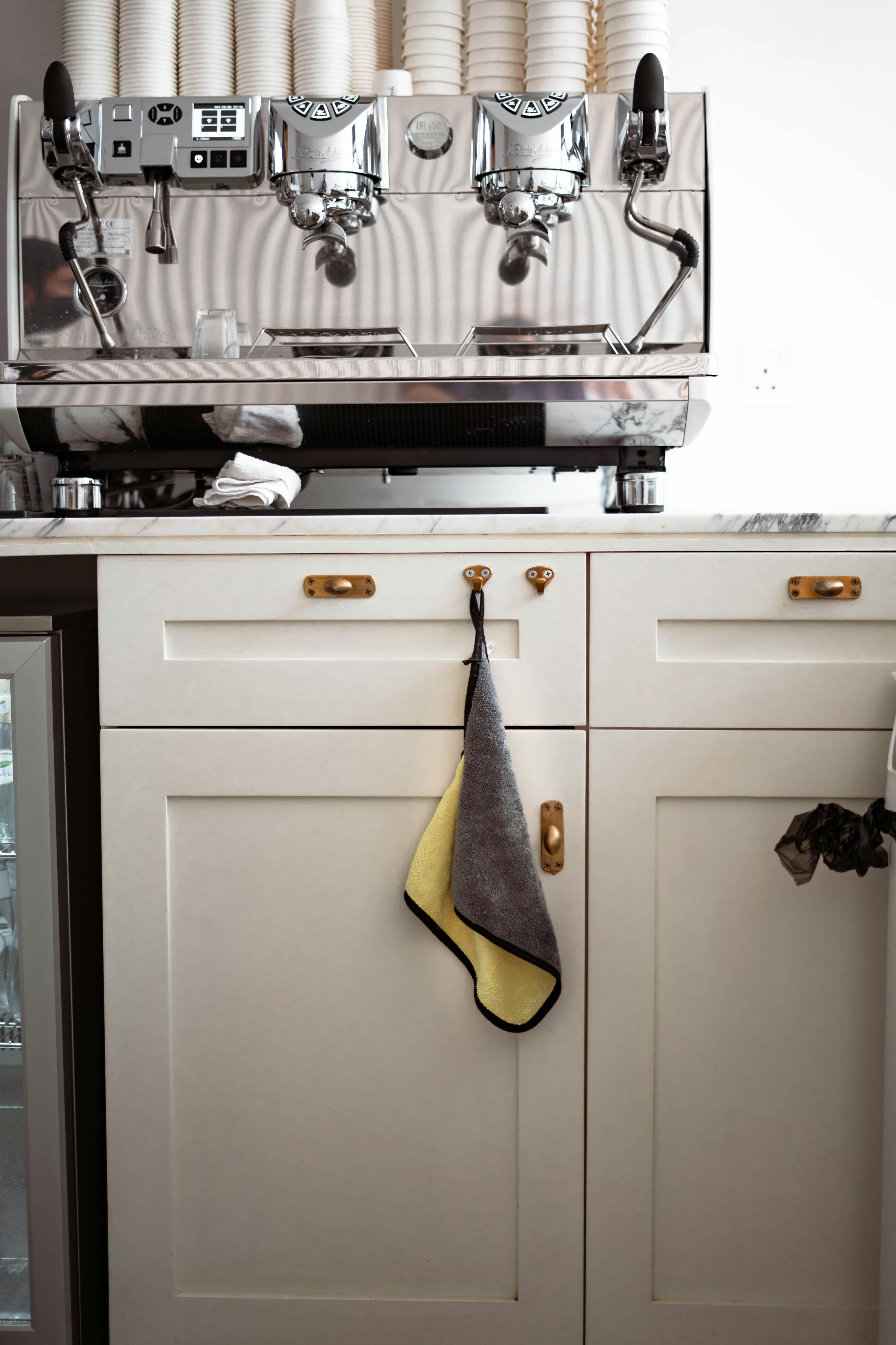 Espresso machine positioned on a clean kitchen counter with cups ready for coffee preparation