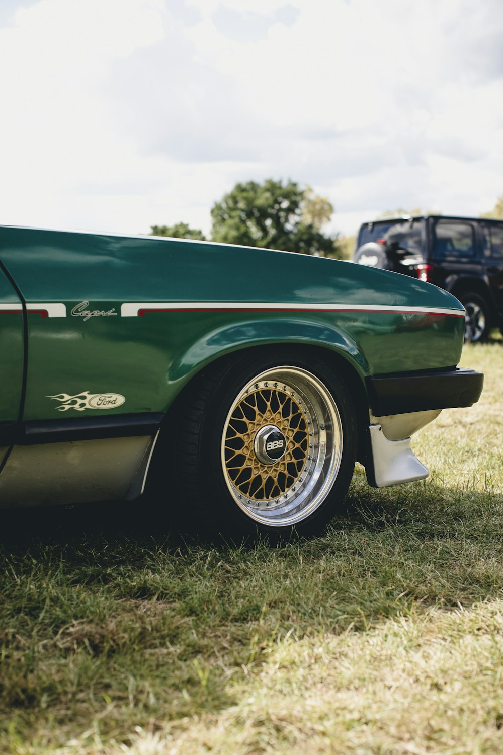 a green car parked on top of a lush green field