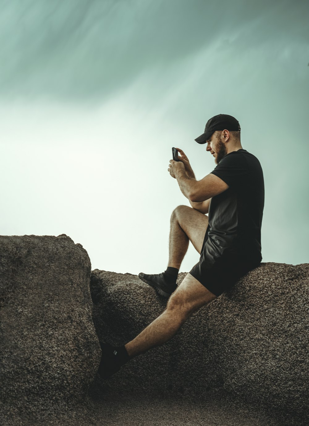 a man sitting on a rock looking at his cell phone