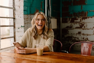 a woman sitting at a table with a cell phone