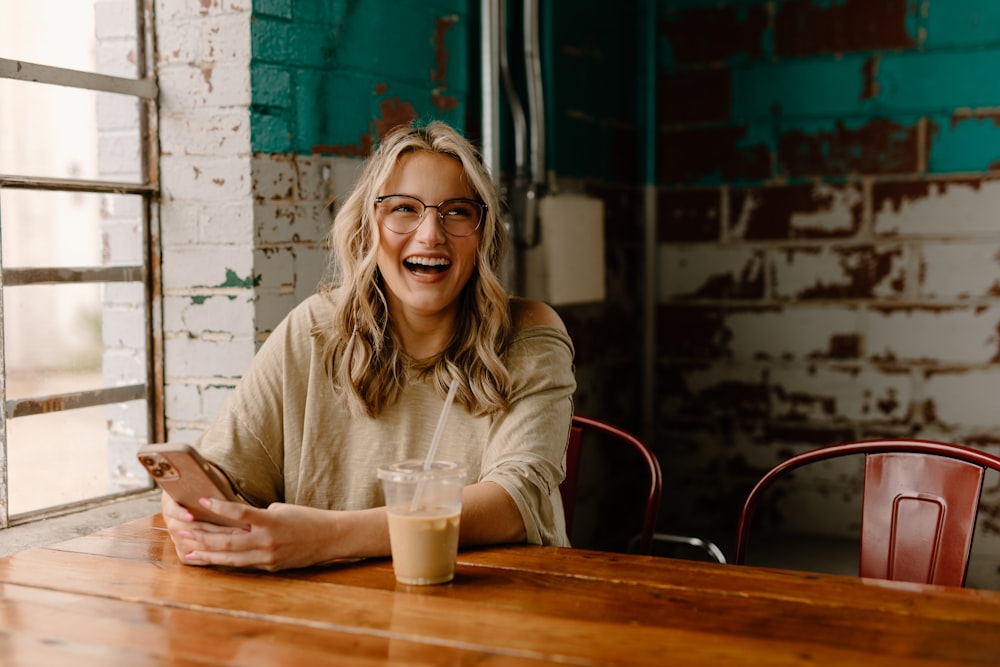 a woman sitting at a table with a cell phone