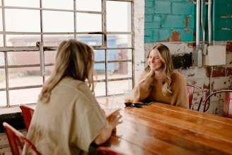 a woman sitting at a table talking to another woman