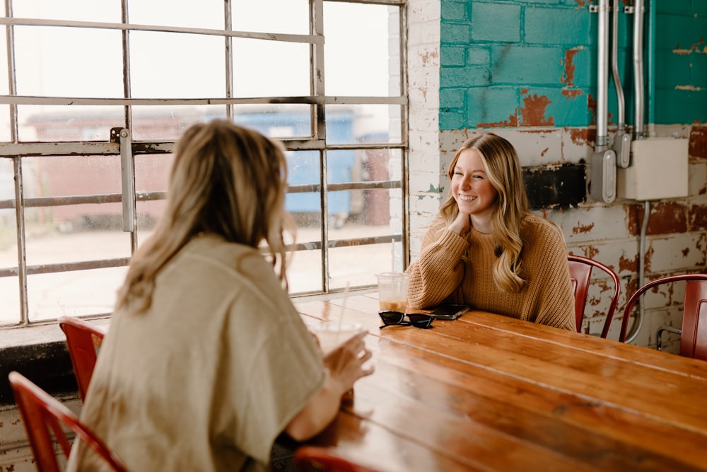 a woman sitting at a table talking to another woman