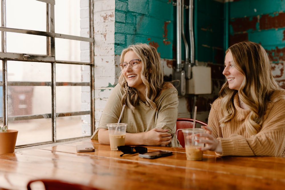 a couple of women sitting at a wooden table